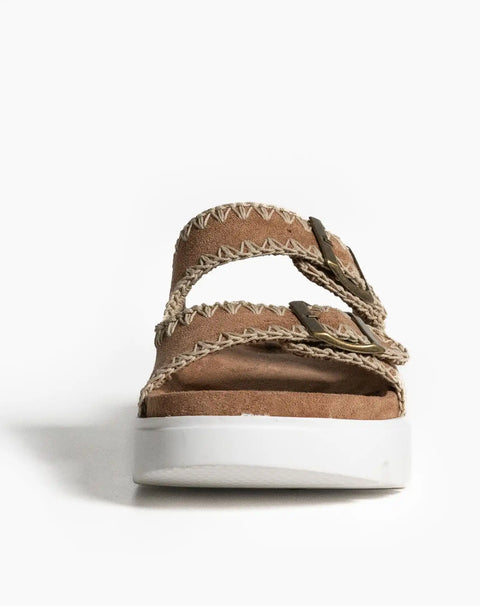 Brown leather sandal with decorative stitching on a white platform sole.